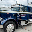 Vintage navy blue Peterbilt semi-truck with Betcher branding parked at an industrial lot