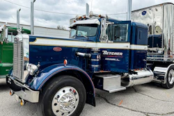 Vintage navy blue Peterbilt semi-truck with Betcher branding parked at an industrial lot