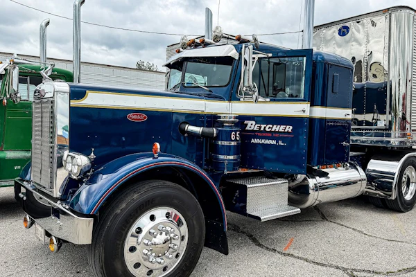 Vintage navy blue Peterbilt semi-truck with Betcher branding parked at an industrial lot