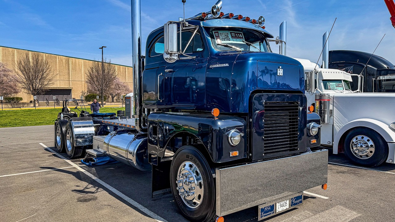 Vintage blue and black semi-truck with polished chrome details displayed at outdoor truck show