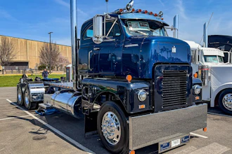 Vintage blue and black semi-truck with polished chrome details displayed at outdoor truck show