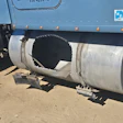 Industrial tanker truck with cylindrical metal tank and circular opening mounted on chassis