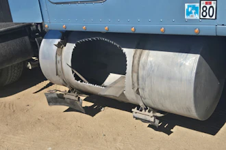 Industrial tanker truck with cylindrical metal tank and circular opening mounted on chassis