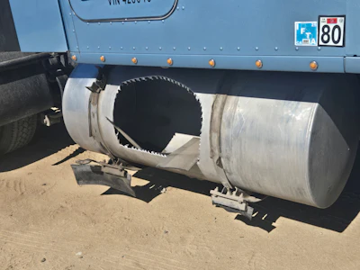 Industrial tanker truck with cylindrical metal tank and circular opening mounted on chassis