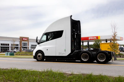 White Tesla Semi truck parked at commercial facility with Penske fuel station in background