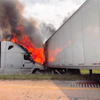 Commercial truck engulfed in flames with heavy black smoke billowing from the cab during roadside fire emergency.