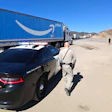 Police officer inspecting Amazon Prime delivery truck on desert highway with vehicles in background