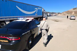 Police officer inspecting Amazon Prime delivery truck on desert highway with vehicles in background