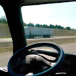 View from truck cab on highway with steering wheel and another truck ahead on the road