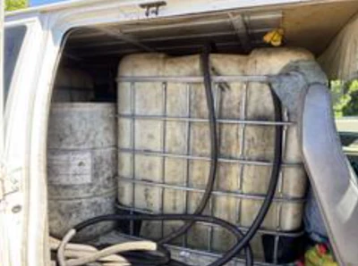 White van interior loaded with secured hay bales using black cargo straps and netting