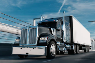 Black and white semi-truck with cargo trailer driving on highway under blue sky