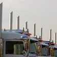Fleet of semi-trucks lined up showing chrome exhaust stacks and cab designs against overcast sky