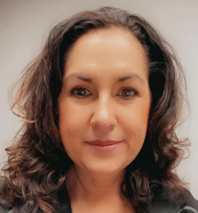 Professional headshot of a woman with shoulder-length brown wavy hair against a neutral background