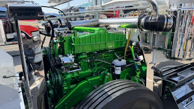 Bright green diesel engine on display at outdoor vehicle show with chrome components and equipment visible