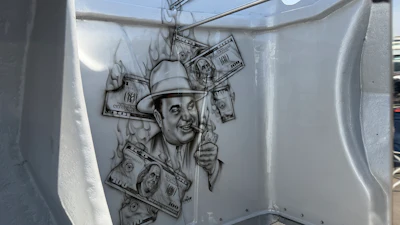 Street art mural of a smiling man in a hat surrounded by dollar bills and smoke effects