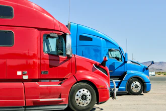 Red and blue semi-trucks parked side by side in an outdoor lot with clear sky