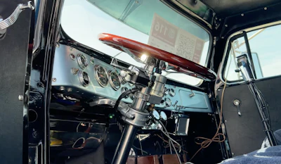 Classic hot rod interior featuring polished dashboard, steering wheel, and custom gauges with windshield visible