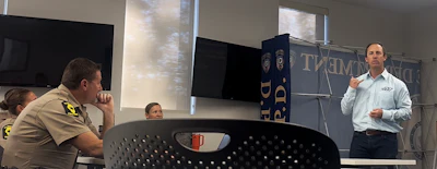 Professional presenting at podium during indoor meeting with attendees seated nearby